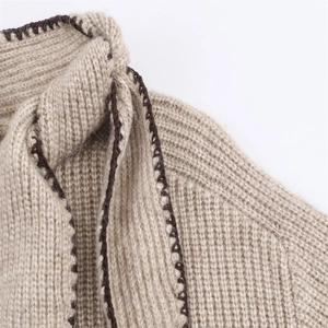 Détail du cardigan en maille côtelée avoine avec broderie contrastée au point de feston