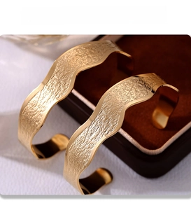 Detail of PVD electroplated gold wavy cuff bracelet with a hammered texture finish