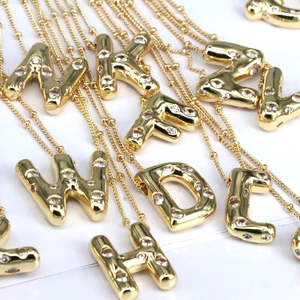 Macro view of gold 18k letter pendants with zircon stones scattered on white background