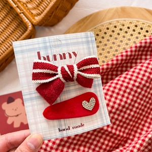 Detail of red bow hair clip set with white stripes and rhinestone heart on card