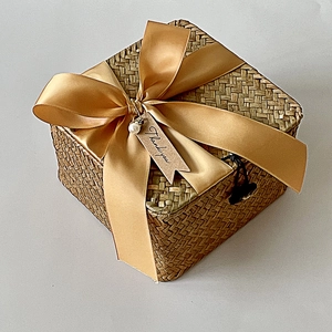 Handwoven rattan gift box with gold satin ribbon and decorative pearl details