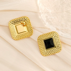 Detailed shot of vintage gold textured square earrings with a black gemstone center