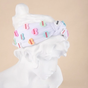 Detail of white plush headband with colorful heart patches and XOXO embroidery