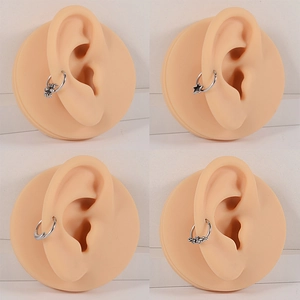 Silver stainless steel nose rings set with spider, star, and moon shapes on ear models