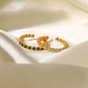 Detail of 18K gold plated beaded open rings with green and white zircon on white silk