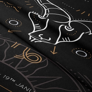 Macro detail of black velvet Capricorn tapestry with golden patterns and white line art