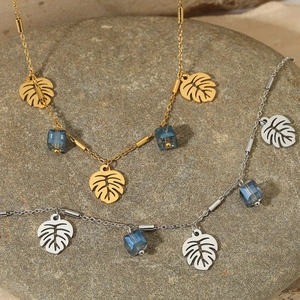 Monstera leaf pendant necklace in gold and steel with square blue crystal beads