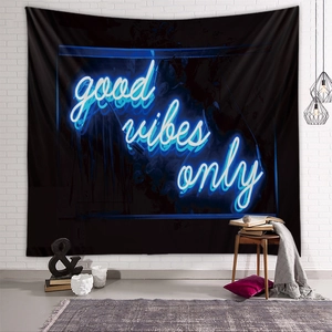 Detail of black tapestry with blue neon Good Vibes Only text on white brick wall