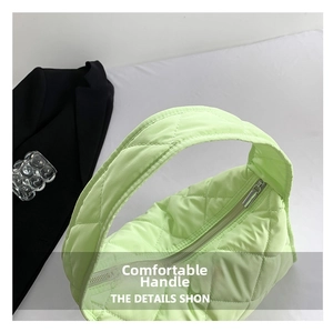 Detail of lime green puffer bag showing quilted nylon fabric and wide shoulder strap