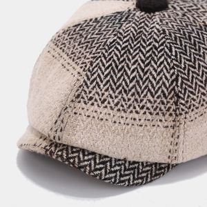 Detailed macro view of herringbone tweed texture and top button on retro baker boy hat