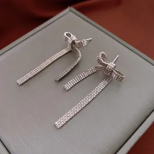 Silver bow tassel drop earrings with delicate chain weaving on velvet background
