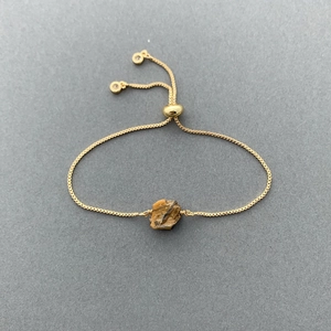 Macro detail of natural brown crystal stone on adjustable 14K gold plated box chain bracelet