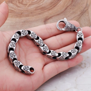 Detail of vintage stainless steel punk bracelet with hollow floral and scroll engravings