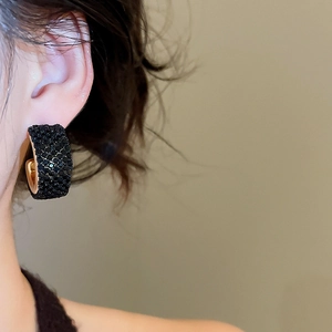 Macro side view of vintage C-shaped gold earrings with black pavé crystals on ear