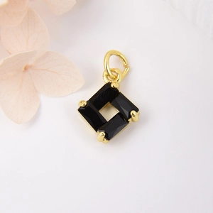 Square gold pendant with black baguette-cut zircons and metal clasp on white background