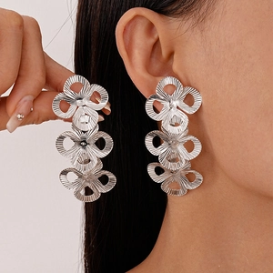 Silver metallic triple tiered hollow flower drop earrings worn by a model in close-up