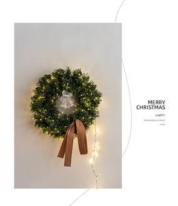 Detail of Christmas wreath with warm LED lights, silver bells and brown fabric bow on wall
