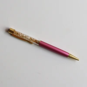 Detail of pink metal ballpoint pen with yellow crystal stones in transparent barrel