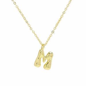 Macro detail of puffy 18k gold plated letter M bubble pendant with polished finish