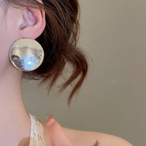 Gros plan de boucles d'oreilles circulaires argentées polies avec finition miroir