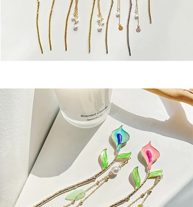 Detailed view of metal hairpins with enamel calla lily designs and pearl tassels