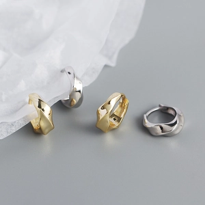 Macro shot of minimalist twisted S925 silver hoop earrings in gold and silver finishes