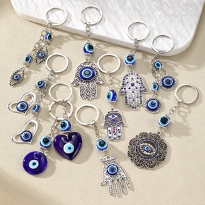 Detail of nine Hamsa Hand and Evil Eye keychains with blue beads and silver finish