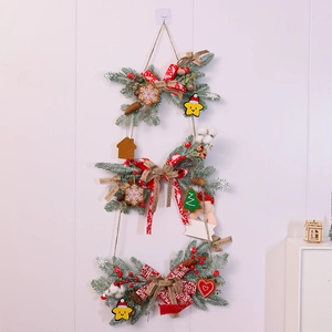 Detailed view of 3-tier Christmas garland with pine needles, red berries, and gingerbread charms