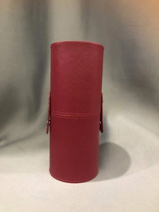 Close-up of red faux leather makeup brush holder with fine stitching and metal snap button