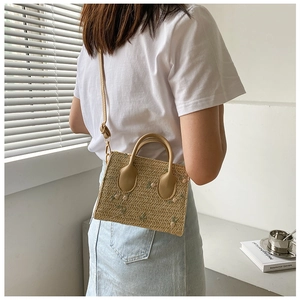 Detail of straw woven crossbody bag with floral embroidery and adjustable PU strap