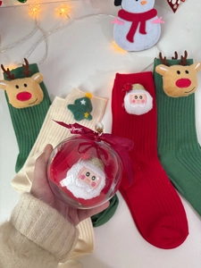 Close-up of festive Christmas socks in creative ball packaging with ribbon and 3D doll details