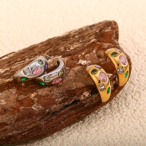 Macro detail of gold and silver C-shaped earrings with colorful inset zircon stones