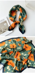 Detail of silk scarf with orange floral pattern on dark green satin fabric texture