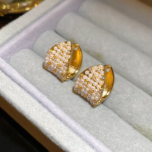 Close-up of gold-plated hoop earrings with micro-paved white pearls in a jewelry box
