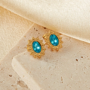 Macro shot of gold stainless steel stud earrings featuring oval blue zircon sunburst design