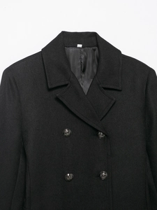 Detail of black double-breasted wool coat with embossed metal buttons and twill texture