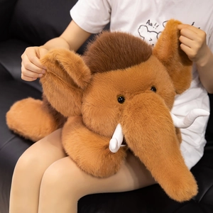 Plush mammoth toy in brown with white tusks, held by a person for size display