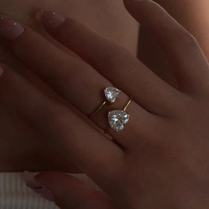 Close-up of golden open heart ring with sparkling diagonal zirconia stones on hand