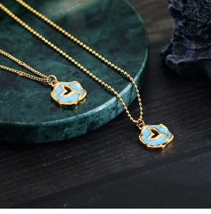 Macro detail of gold fish tail pendants with blue enamel on green marble tray