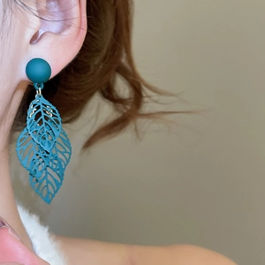 Detail of dark green matte leaf earrings with hollow textures on a model's ear