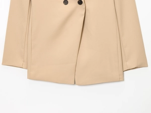 Detailed close-up of khaki blazer hem and buttons against a white background
