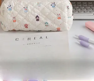 Quilted white stationery pouch with cute cartoon prints and zipper, shown on a desk