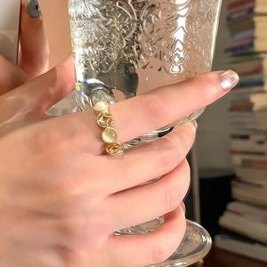 Vintage gold hollow resin ring with yellow gemstones shown on a finger with a glass