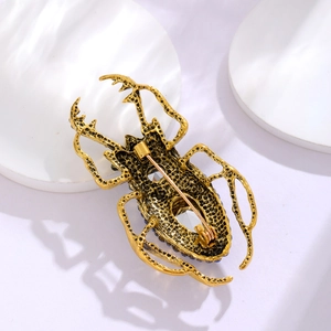 Punk beetle brooch with gold hollow metal, blue beads and clear crystal on white stand