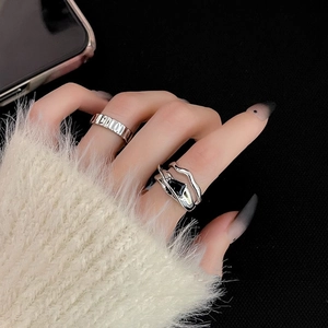 Close-up of minimalist silver rings with black zircon on hand against dark background