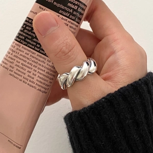 Close-up of minimalist silver twist rope ring on thumb with lifestyle background