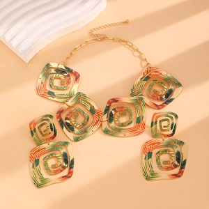Détail de la parure carrée dorée avec motifs de feuilles tropicales sur le collier