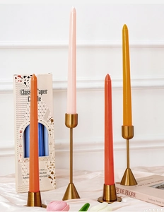 Detalle de velas cónicas de 10 pulgadas en colores con soportes de metal sobre tela de seda