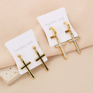 Close-up of gold and black cross stud earrings with zircon on a marble display