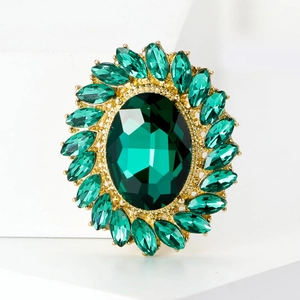 Detailed macro view of green crystal sunflower brooch with vintage oval emerald gemstone